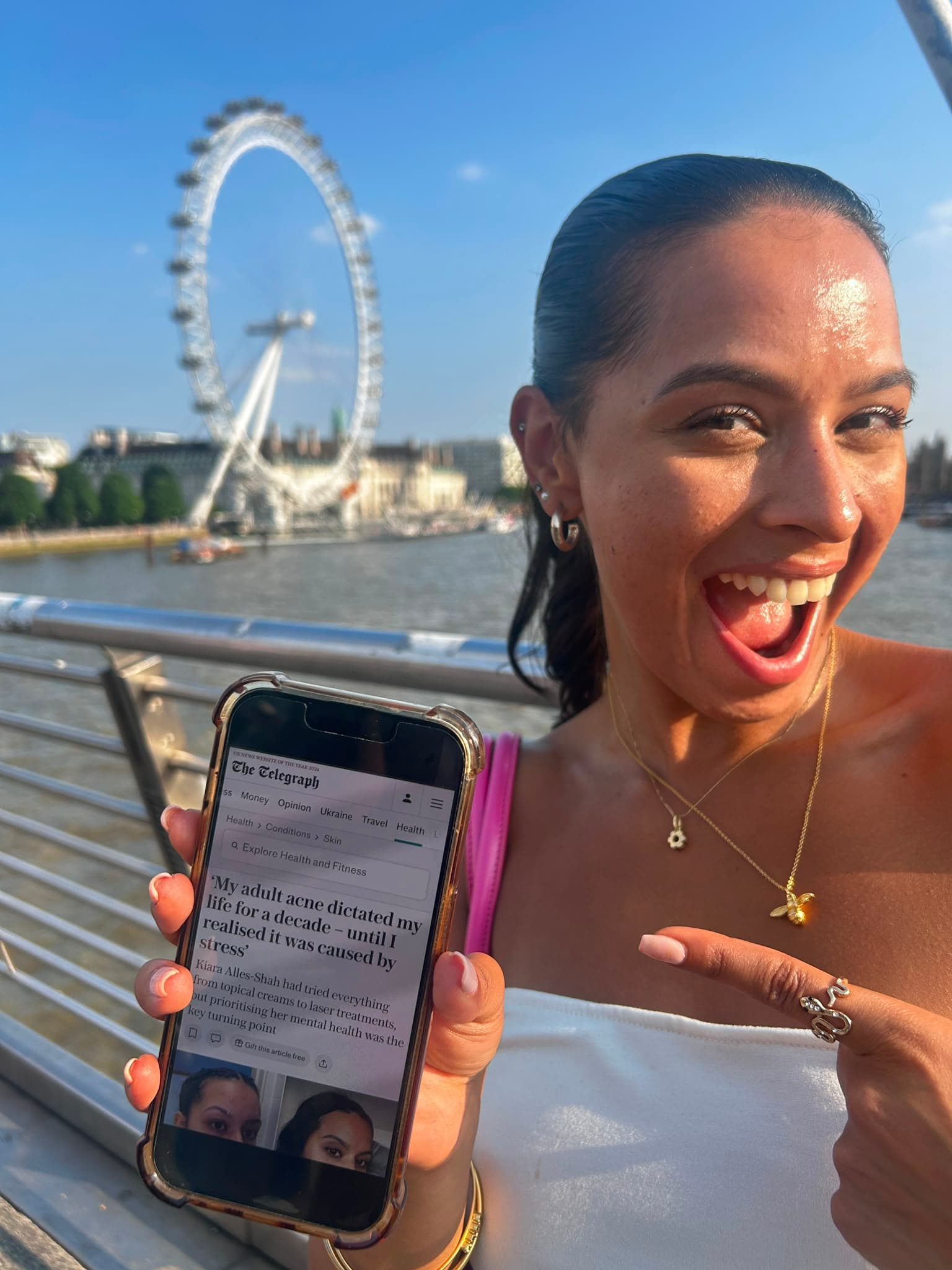 Kiara holding her phone with The Telegraph feature, London Eye behind her